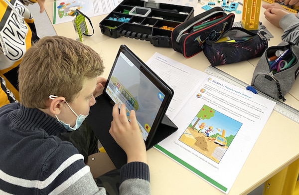 enfant programmant un robot depuis un tablette
