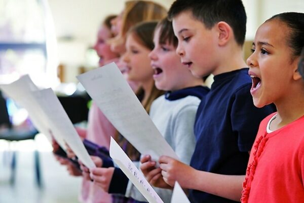 enfants chantant en chorale avec partitions