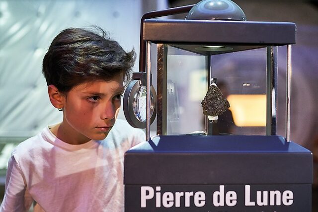 Élève observe pierre de lune dans un musée
